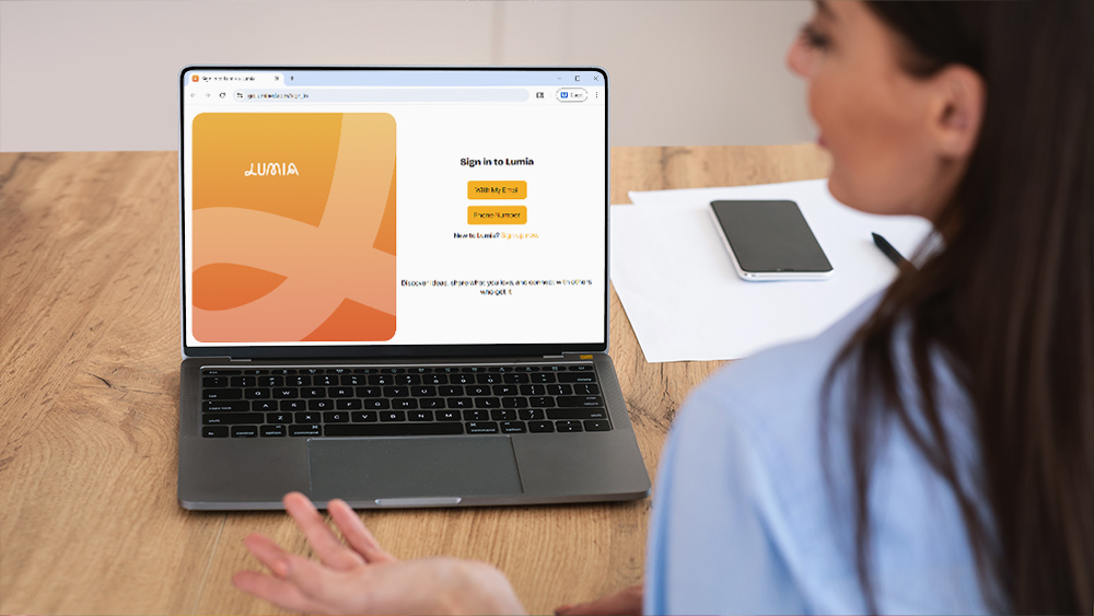 A teacher sitting in front of a laptop with the Lumia login screen