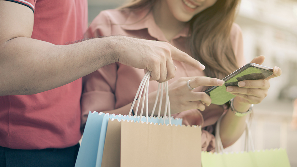 Two people shopping while looking at a mobile app